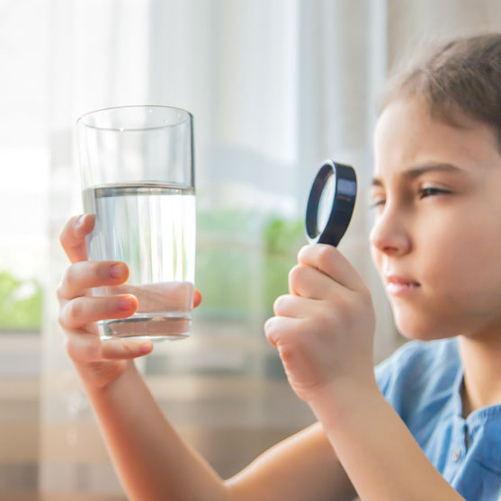 Girl examining glass of water